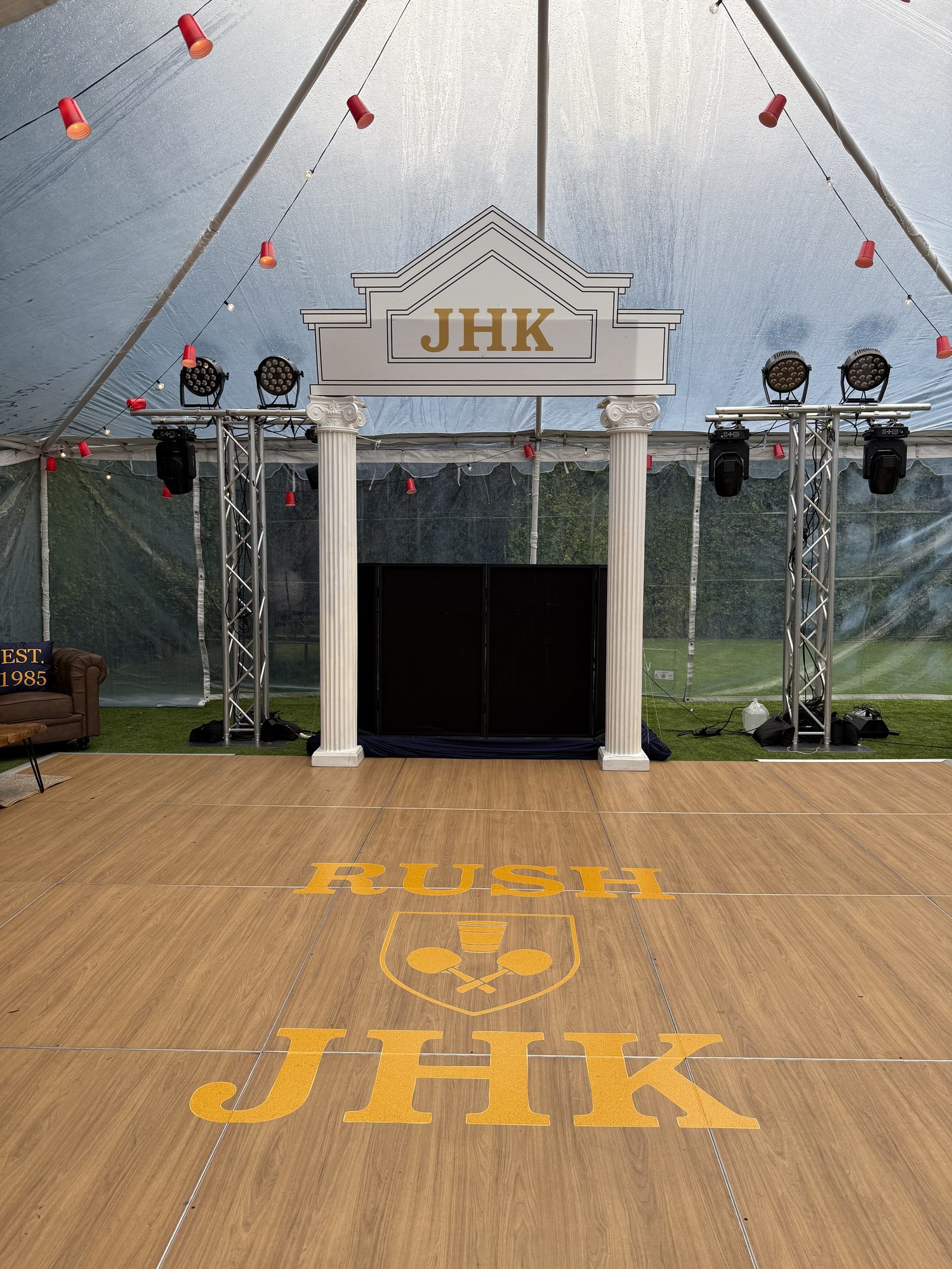 Wood-look vinyl dance floor with custom cut crest and letter decals for a Greek life event