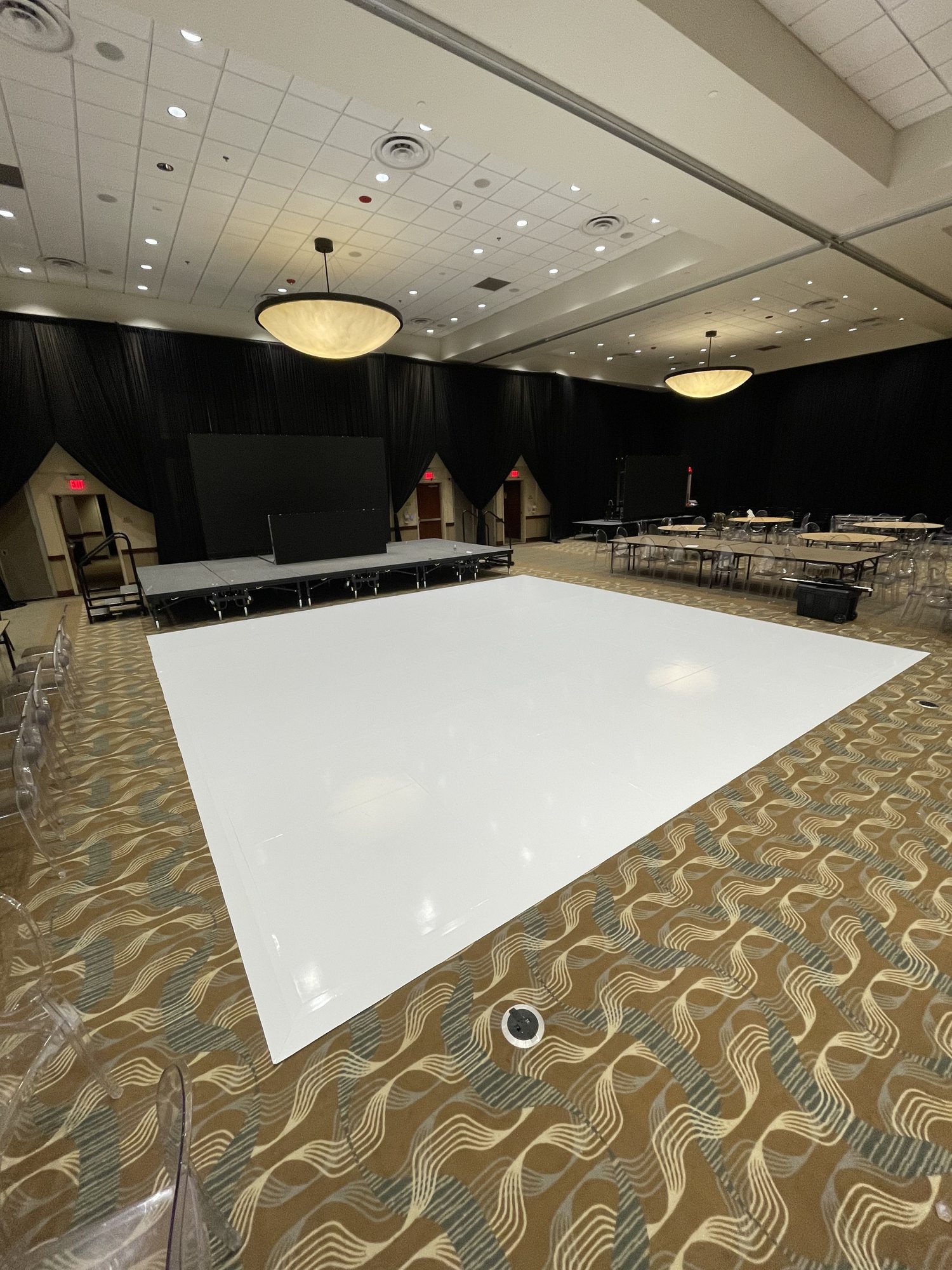 White gloss vinyl dance floor, cut to size, surrounded by ghost chairs at a wedding reception