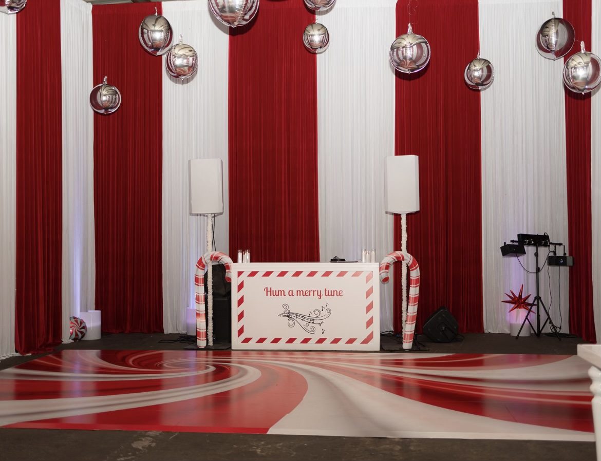 Printed red and white candy cane stripe dance floor at a holiday party DJ booth